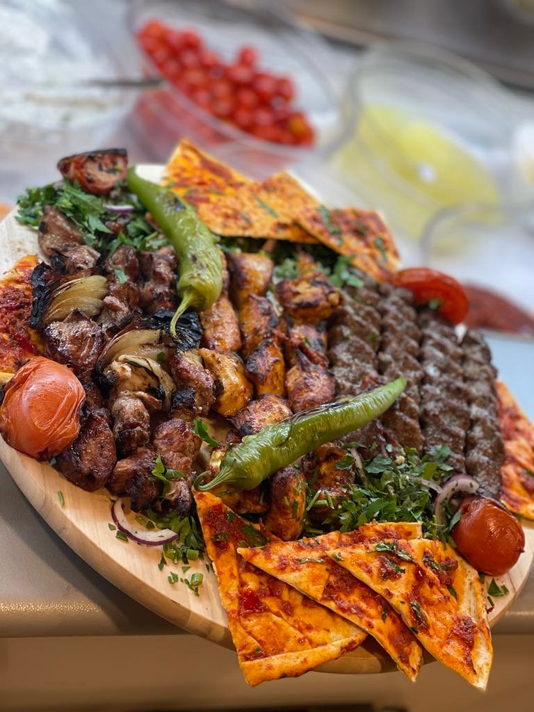 Familie grill ret med spyd, lahmacun og salat på træfad